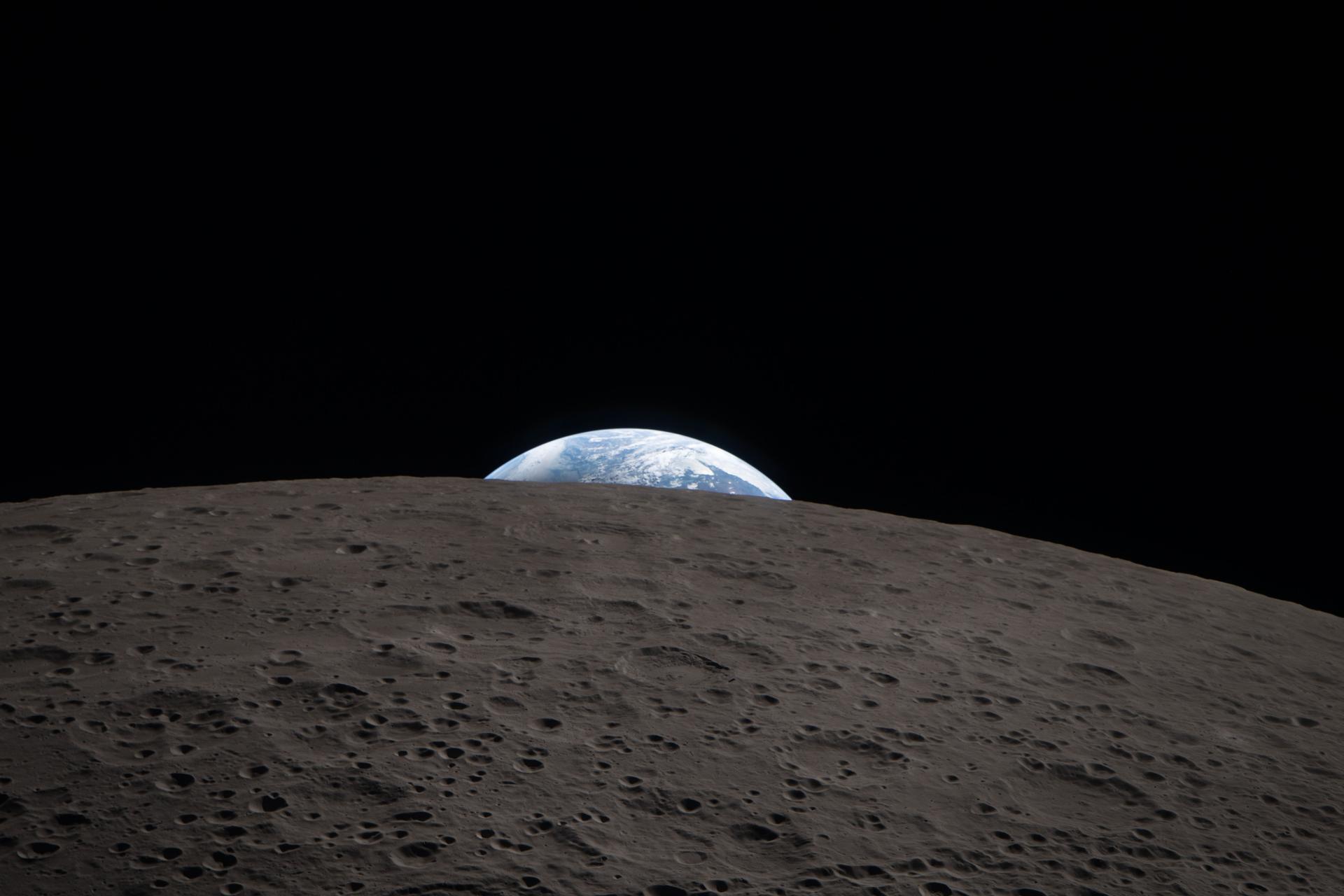 Earthrise photographed from the Artemis II Orion spacecraft — Earth rising above the cratered lunar horizon against the black of space, echoing the iconic Apollo 8 Earthrise of 1968 — April 6, 2026